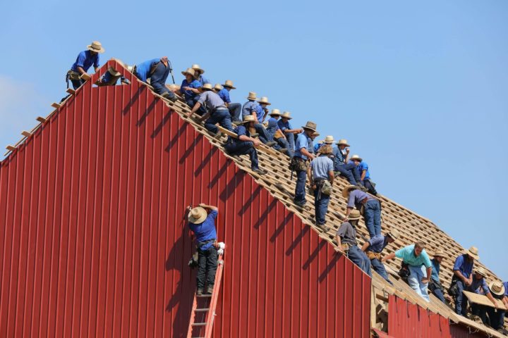 Kymmeniä saman näköisiä miehiä rakentamassa samaa kattoa.